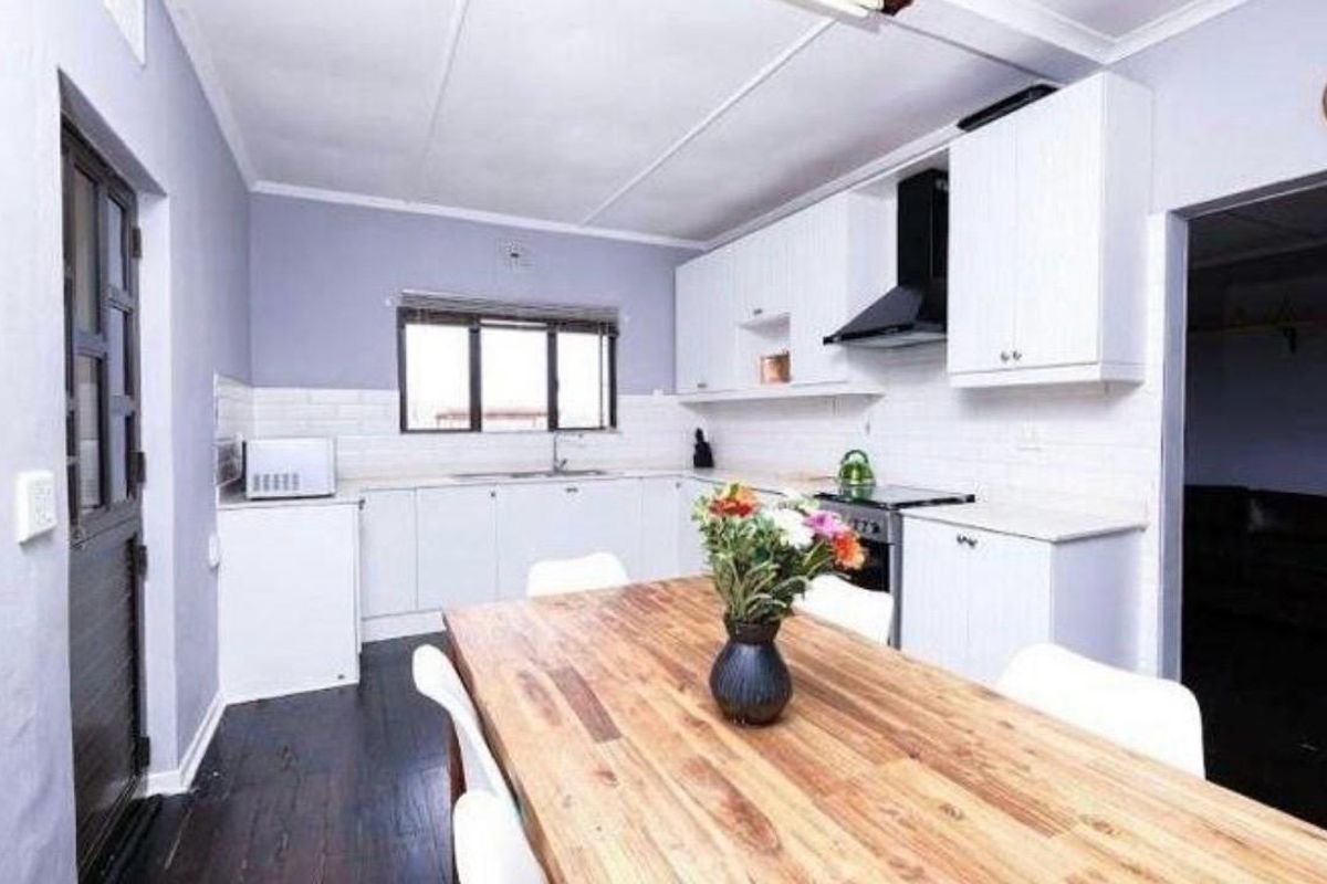 A functional kitchen featuring white cabinetry, subway tile backsplash, integrated extractor fan, and dark laminate flooring, providing a clean and practical cooking space.