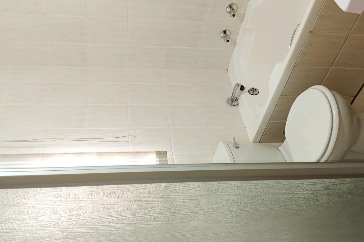 A functional bathroom featuring a bathtub, toilet, and tiled finishes, providing a clean and neutral space ready for potential updates.