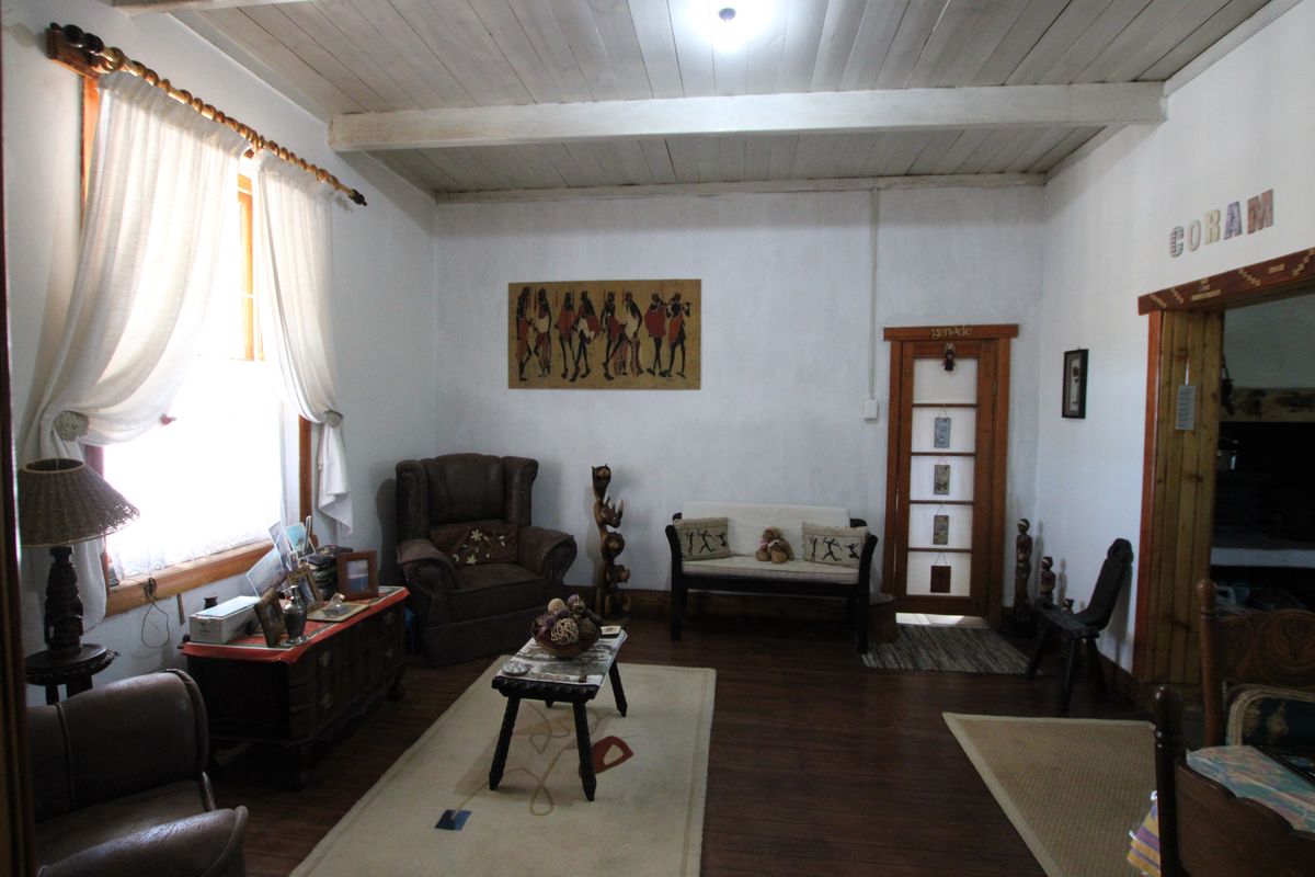 A living room featuring exposed timber ceiling beams, dark wood flooring, and a traditional wooden door frame.