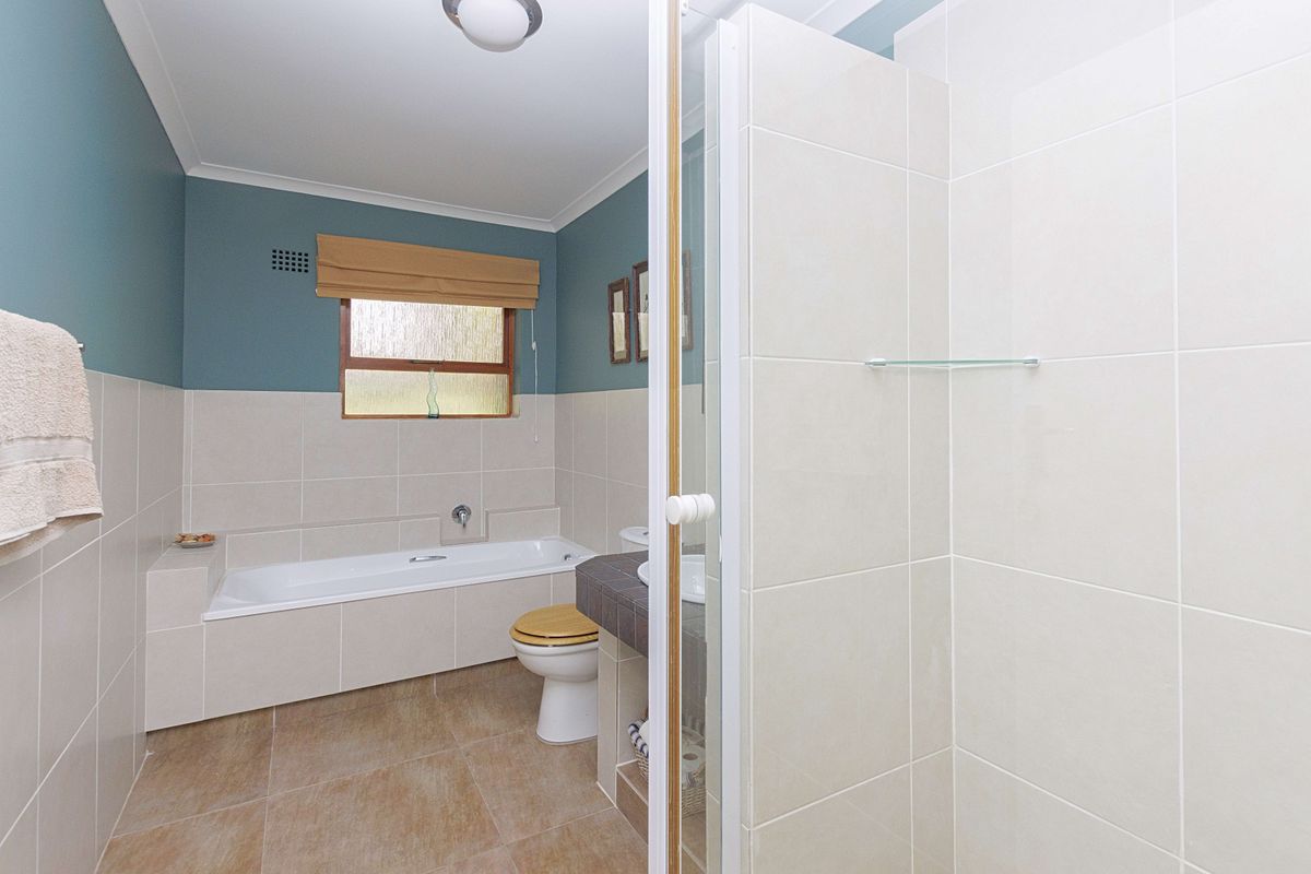 A well-maintained bathroom featuring a built-in bathtub, separate shower enclosure, tiled finishes, and a vanity basin.