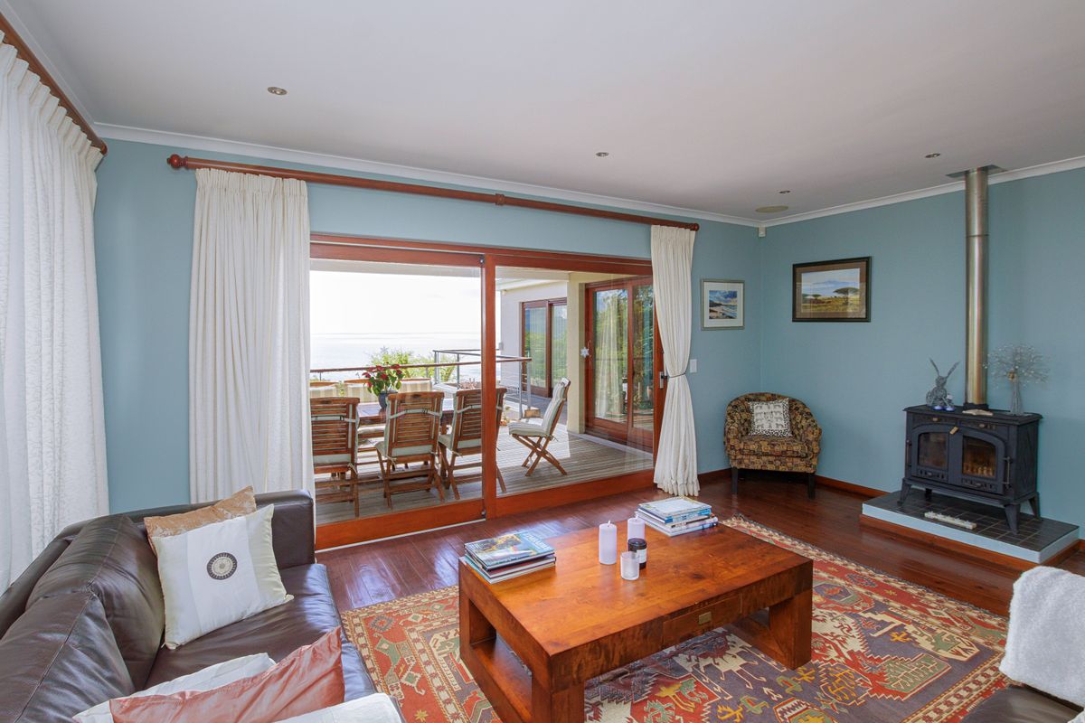 Spacious living room featuring hardwood flooring, a cozy wood-burning stove, and large sliding glass doors that open onto an outdoor patio area.