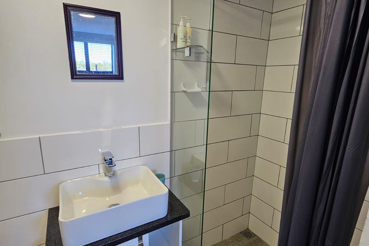 A modern bathroom featuring a vessel sink vanity, a walk-in shower with a glass partition, and subway-style wall tiling.