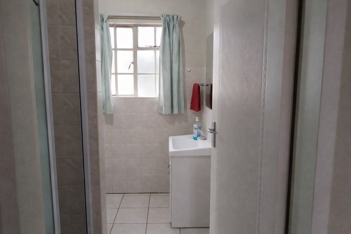 A functional bathroom featuring a vanity basin, tiled wall and floor finishes, and a separate shower enclosure.