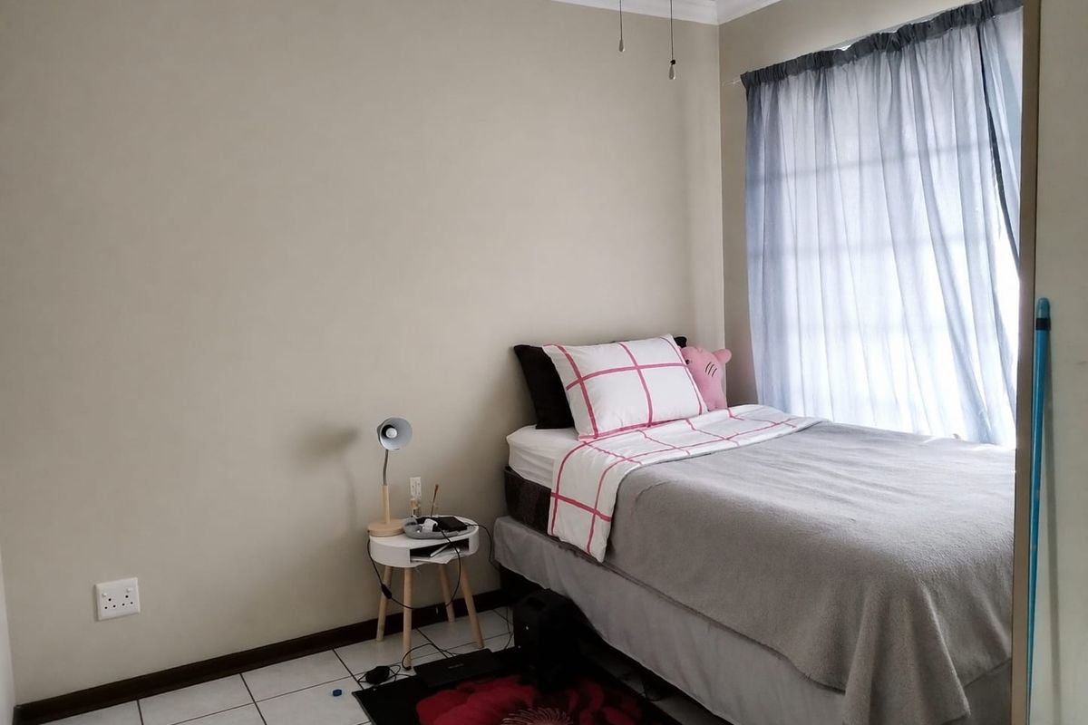 A functional bedroom featuring tiled flooring, neutral wall paint, and a window with curtain treatments.
