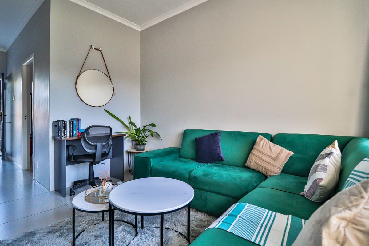 A comfortable living room area featuring tiled flooring and neutral wall finishes, providing a functional space for relaxation and home office use.