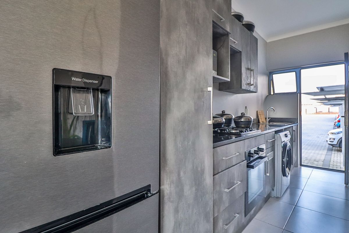 Modern kitchen featuring dark grey cabinetry, integrated oven, gas hob, and a dedicated laundry area with direct access to the exterior.