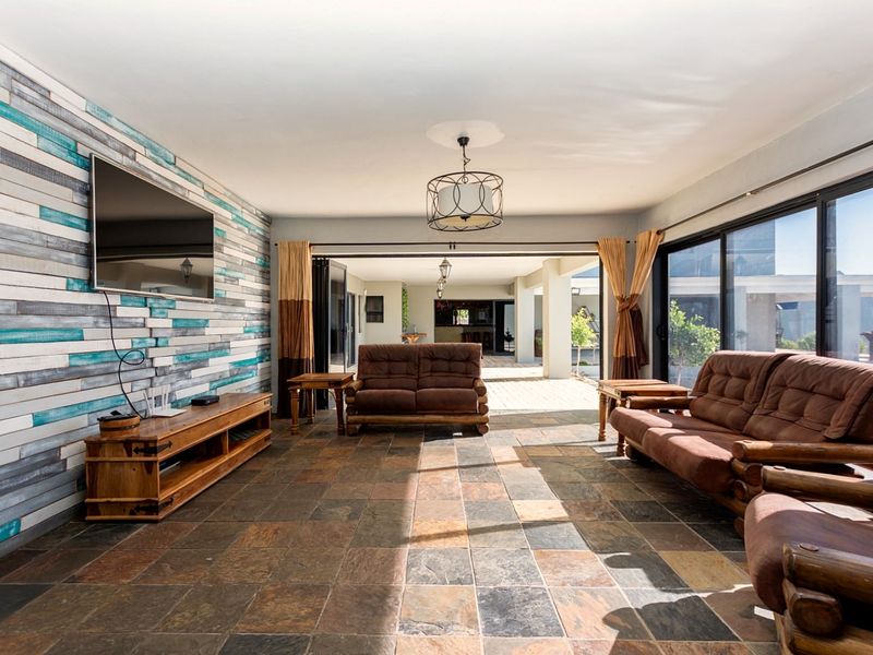 Spacious living area featuring natural stone tile flooring, a decorative wood-paneled feature wall, and large sliding glass doors opening to a covered patio.