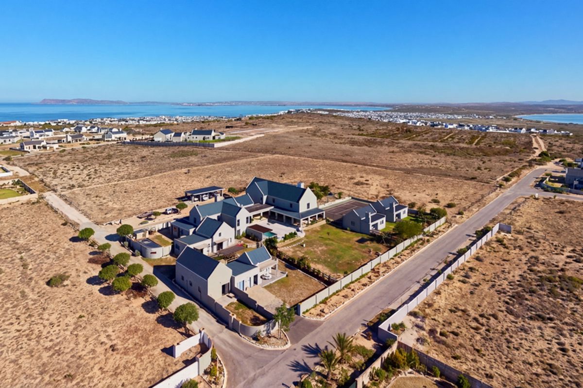 Aerial view of a large coastal residential property featuring multiple interconnected buildings, a swimming pool, and landscaped grounds in a scenic estate setting.