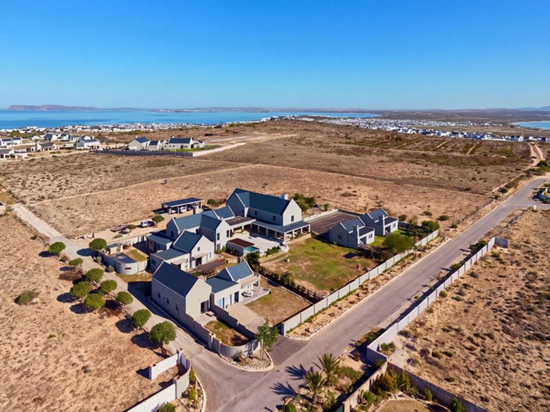 Aerial view of a large coastal residential property featuring multiple interconnected buildings, a swimming pool, and landscaped grounds in a scenic estate setting.