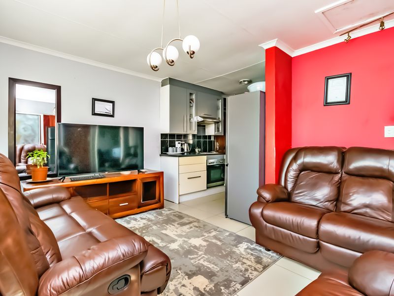 Open-plan living area featuring a compact kitchen with built-in cabinetry, oven, and extractor fan, seamlessly connected to the lounge space.