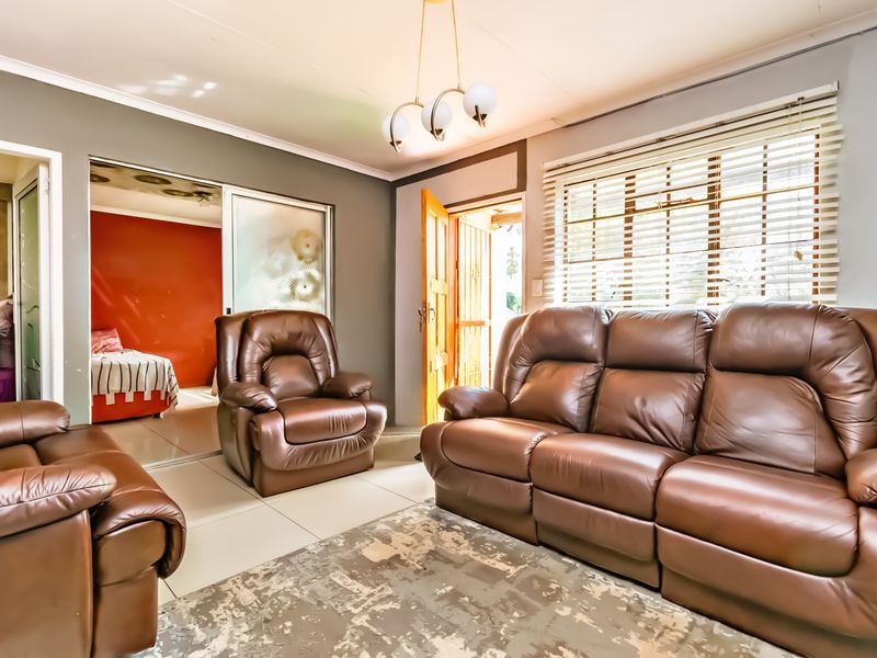 A living room area featuring tiled flooring, a sliding door leading to an adjacent room, and venetian blinds on the window.