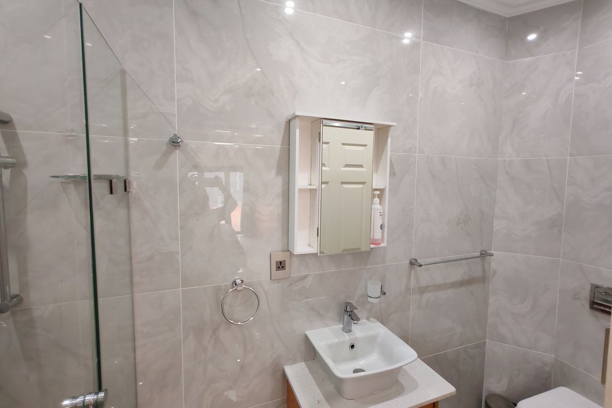 Modern bathroom featuring floor-to-ceiling marble-look wall tiles, a glass shower enclosure, a vessel sink vanity, and a wall-mounted medicine cabinet.