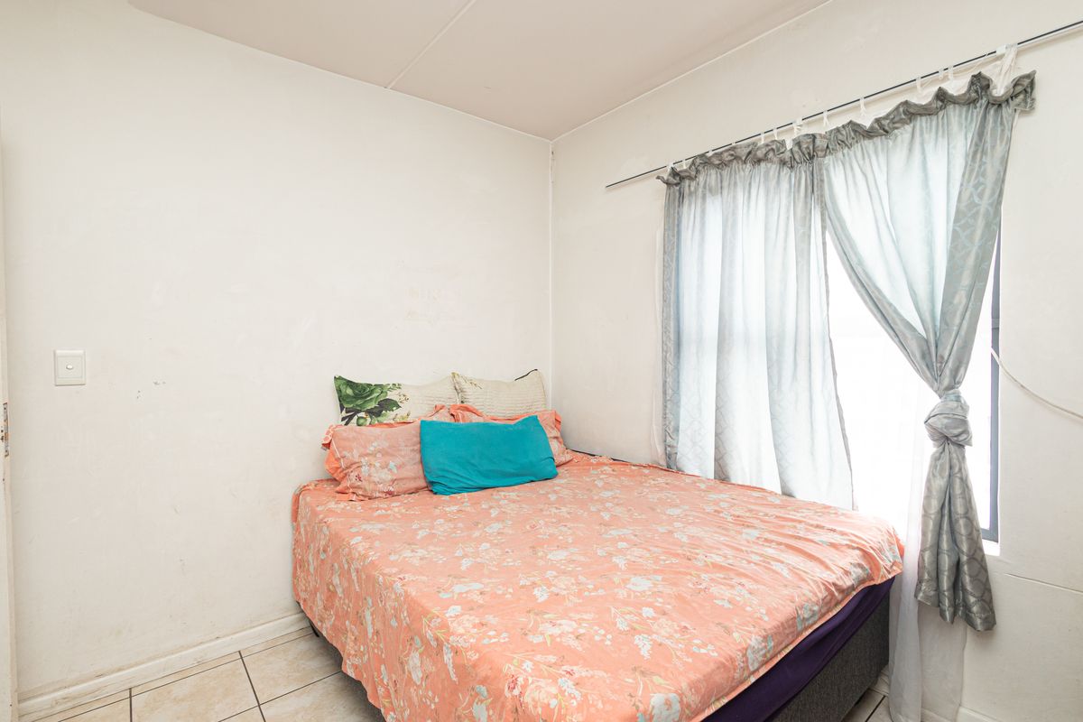 A compact bedroom featuring tiled flooring and a window with curtain track, requiring cosmetic updates to the wall finishes.