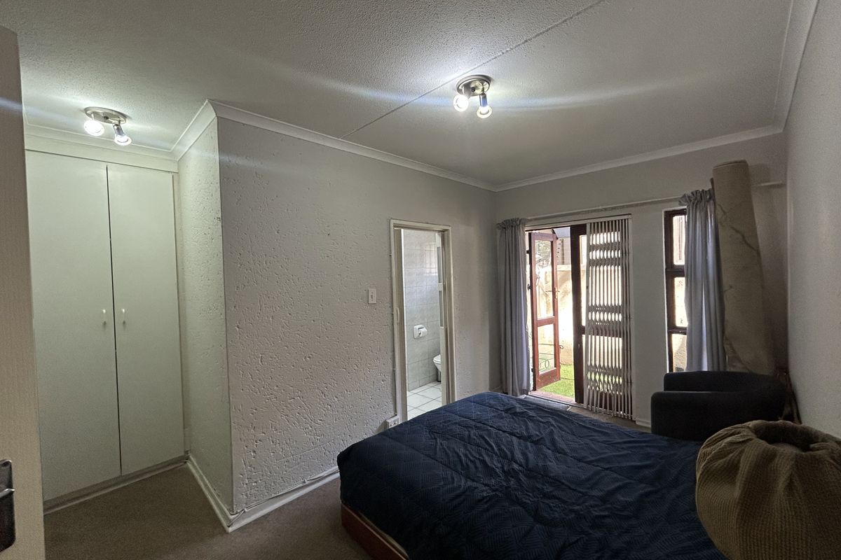 Bedroom featuring built-in cupboards, direct access to an en-suite bathroom, and a glass door leading to an outdoor area.