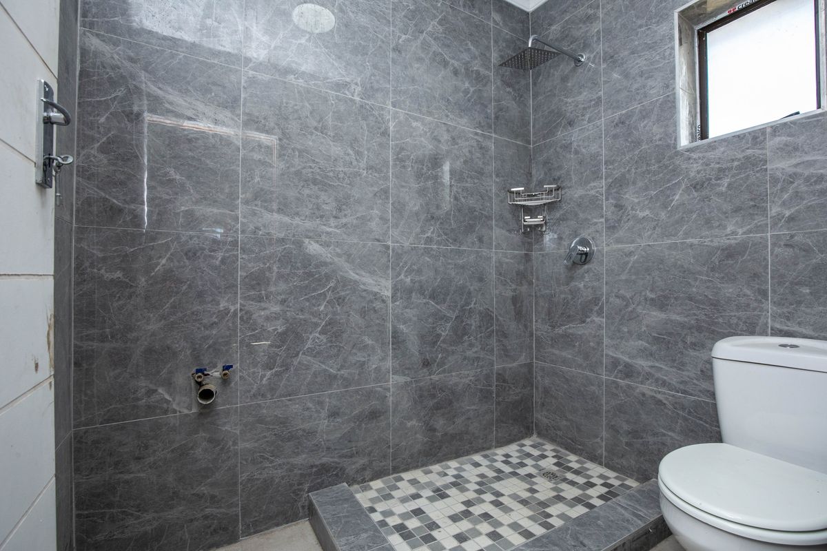 Modern bathroom featuring grey marble-effect wall tiles, a walk-in shower with a rainfall showerhead, and a white toilet.