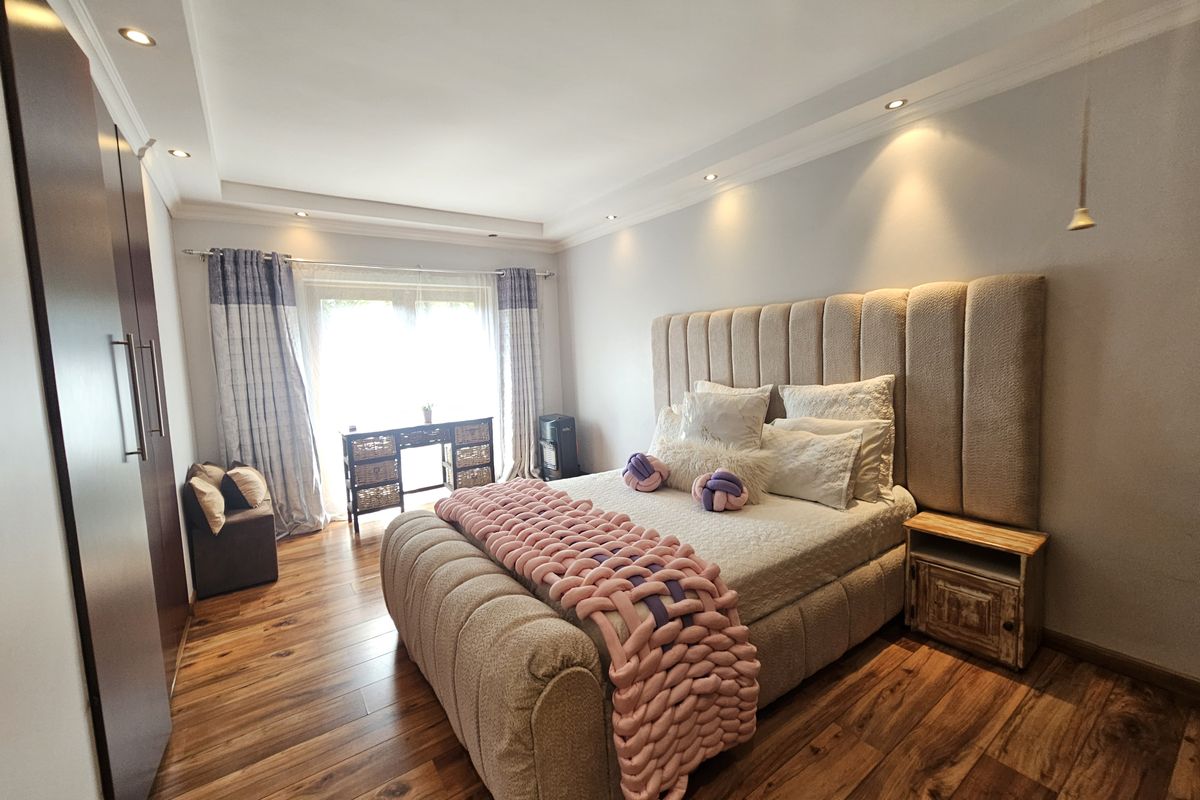 A well-maintained bedroom featuring timber flooring, recessed downlighting, a cove ceiling, and a large built-in wardrobe.
