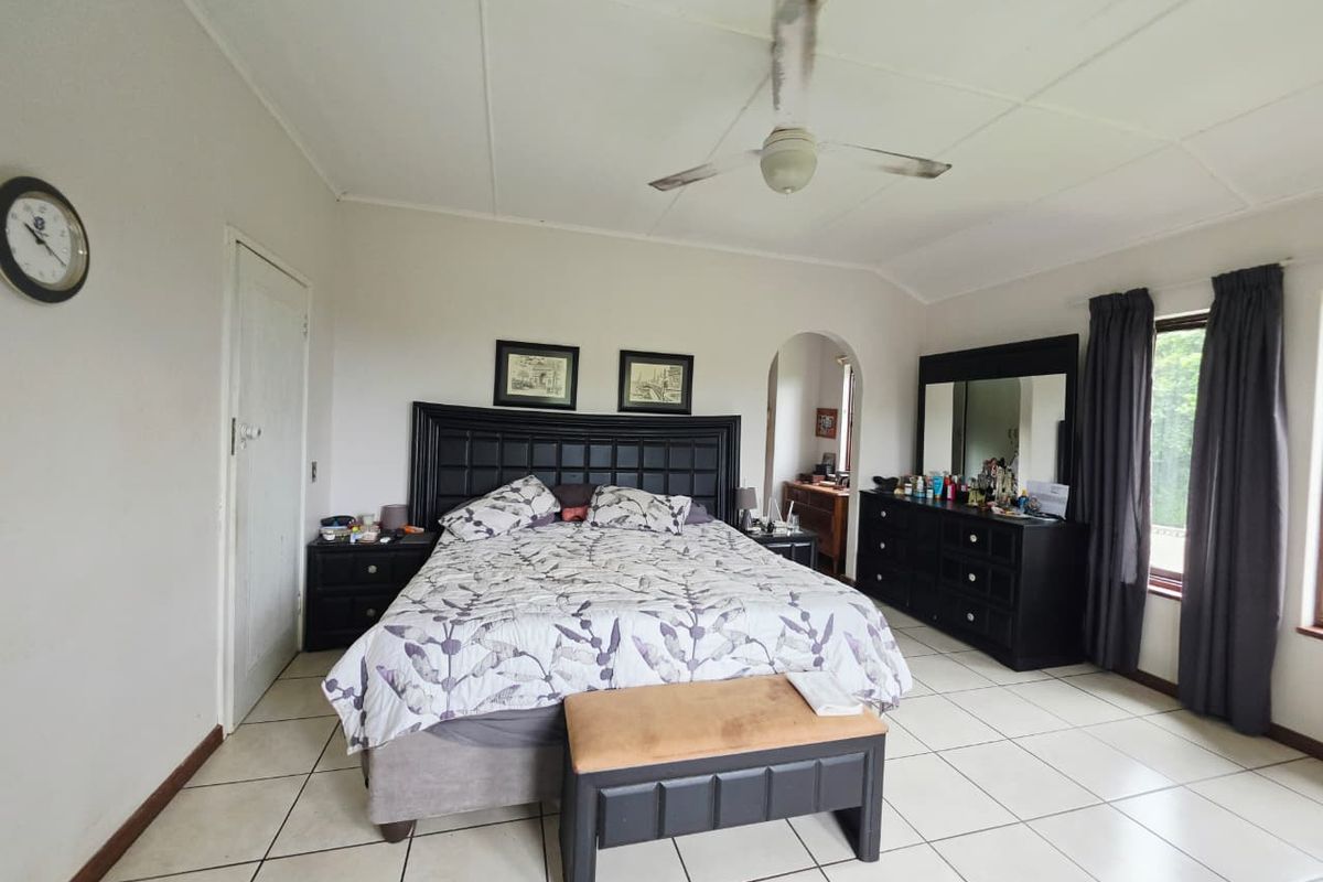 Spacious bedroom featuring tiled flooring, a ceiling fan, and an arched doorway leading to an adjacent area.