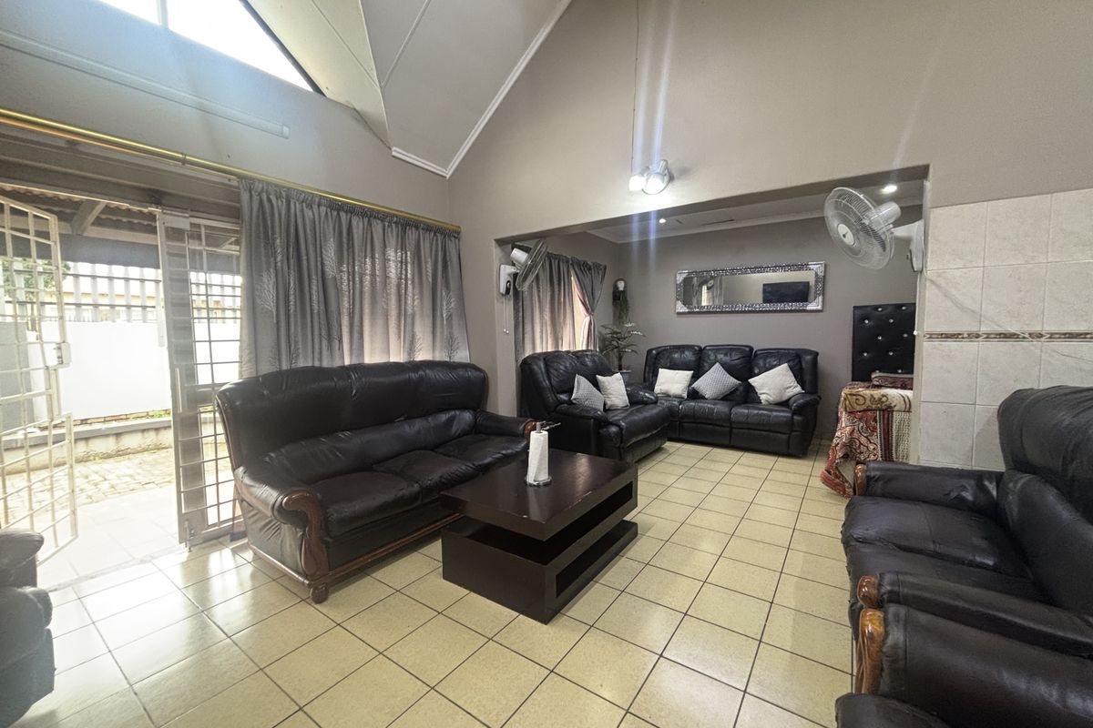 Spacious living area featuring high vaulted ceilings, tiled flooring, and large sliding doors providing direct access to the outdoor patio.