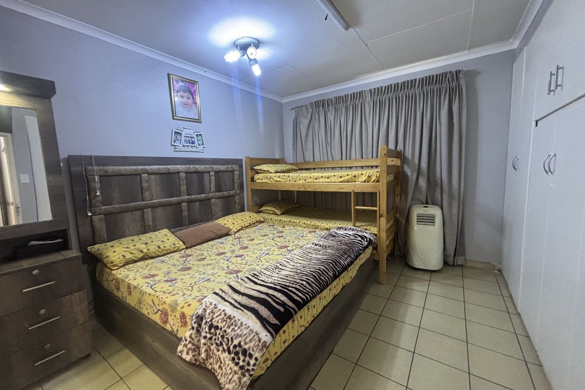 A functional bedroom featuring built-in cupboards, tiled flooring, and a ceiling-mounted light fixture.