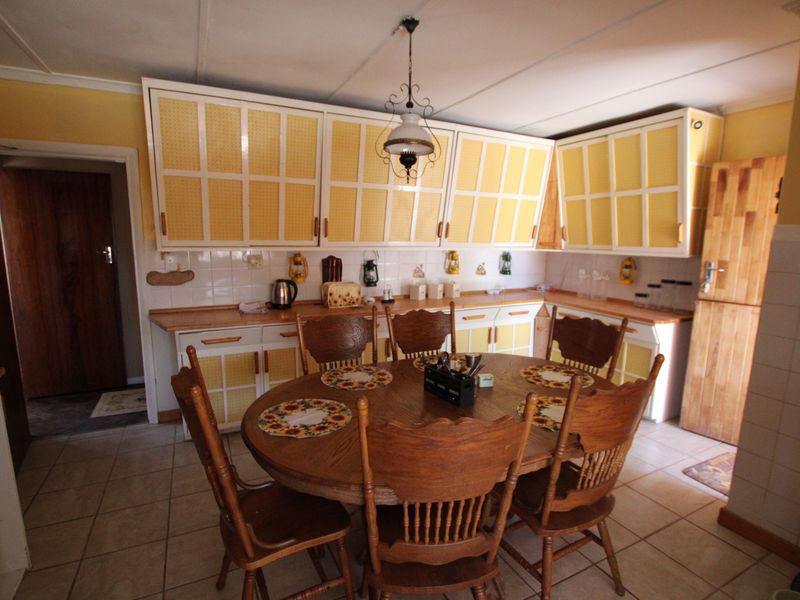 A dated kitchen featuring yellow cabinetry, tiled backsplash, and tiled flooring, offering potential for a modern renovation to enhance the space.