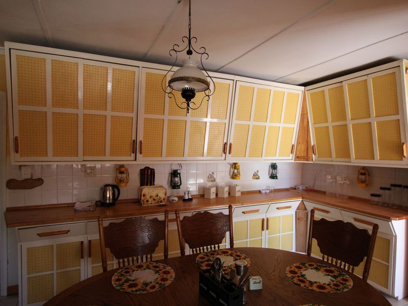 A dated kitchen featuring yellow patterned cabinetry, laminate countertops, and a tiled backsplash, offering potential for a modern renovation.