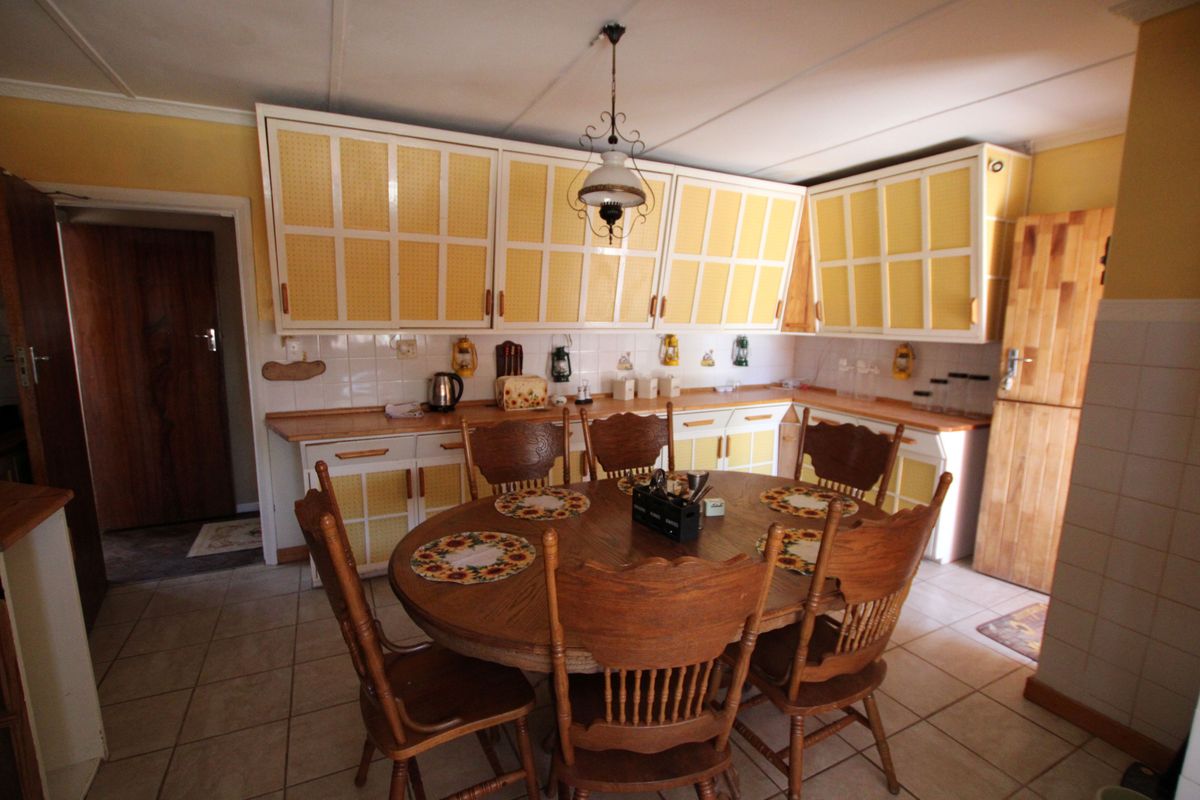 A dated kitchen featuring yellow cabinetry, tiled backsplash, and tiled flooring, offering potential for a modern renovation to enhance the space.