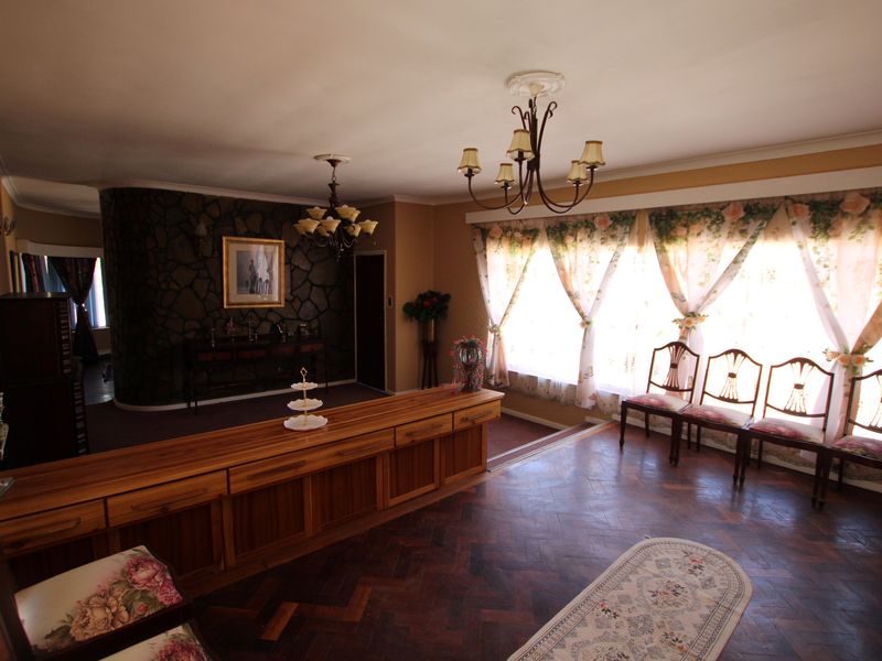 Spacious living area featuring classic parquet flooring, a distinctive stone feature wall, built-in wooden cabinetry, and elegant ceiling chandeliers.