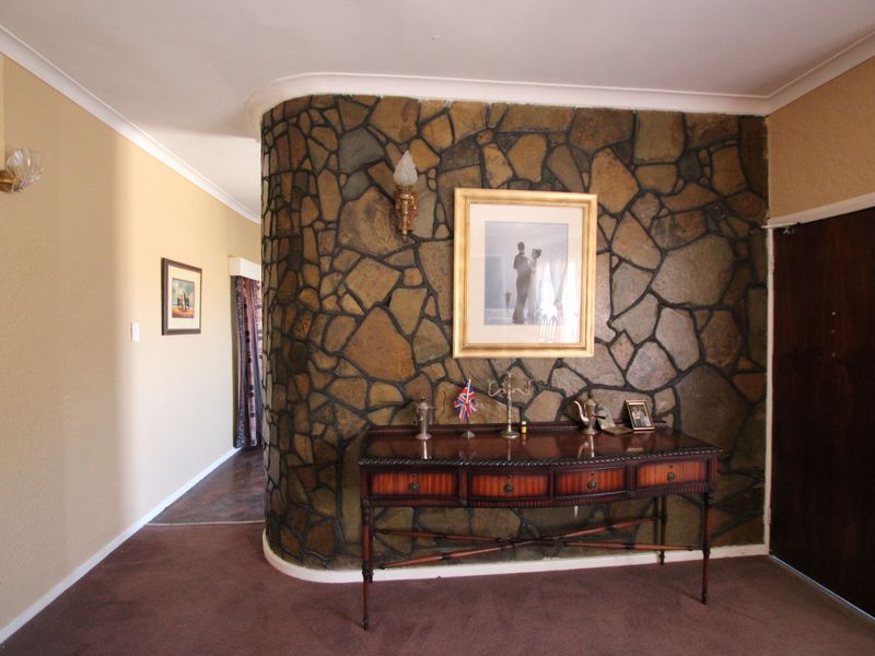 Entrance hall featuring a distinctive curved stone feature wall and classic coving, providing a unique architectural focal point for the home.