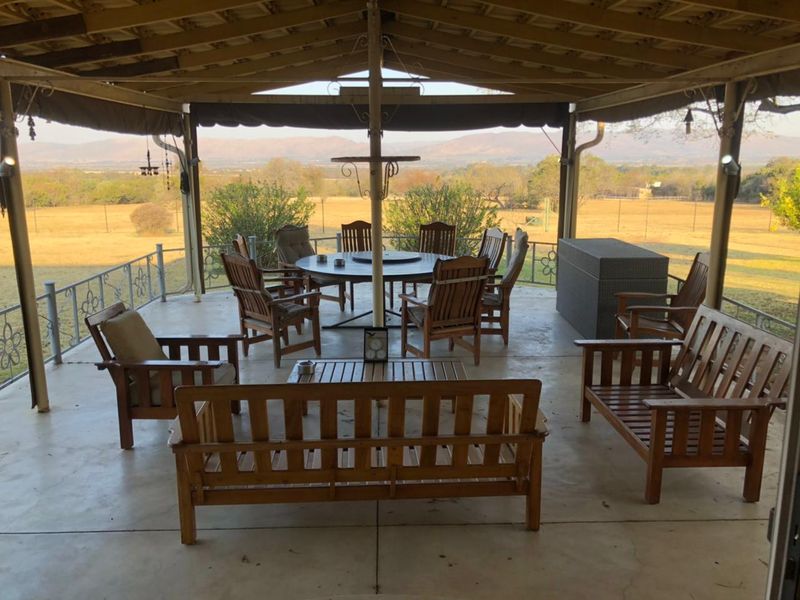 A spacious covered patio featuring concrete flooring and wrought iron railings, offering expansive views of the surrounding landscape.