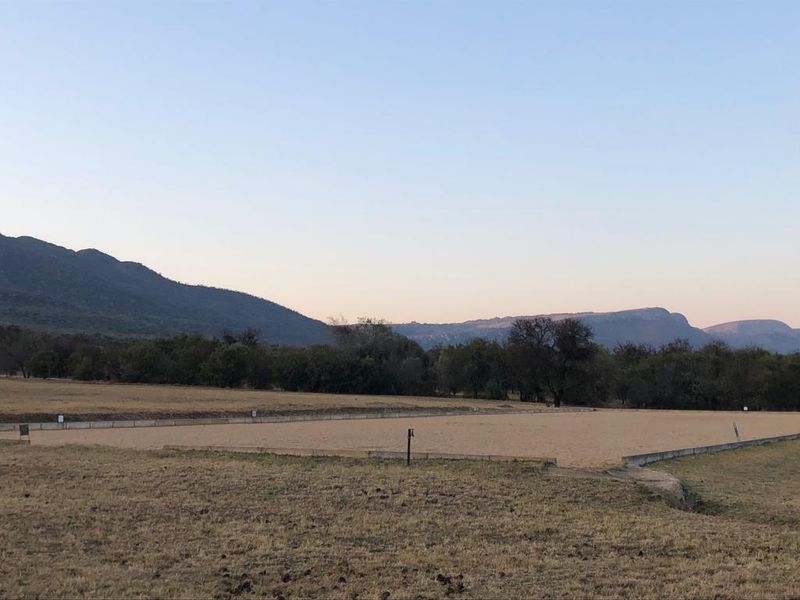 A large outdoor sand riding arena situated on the small holding, featuring mountain views and open landscape surroundings.