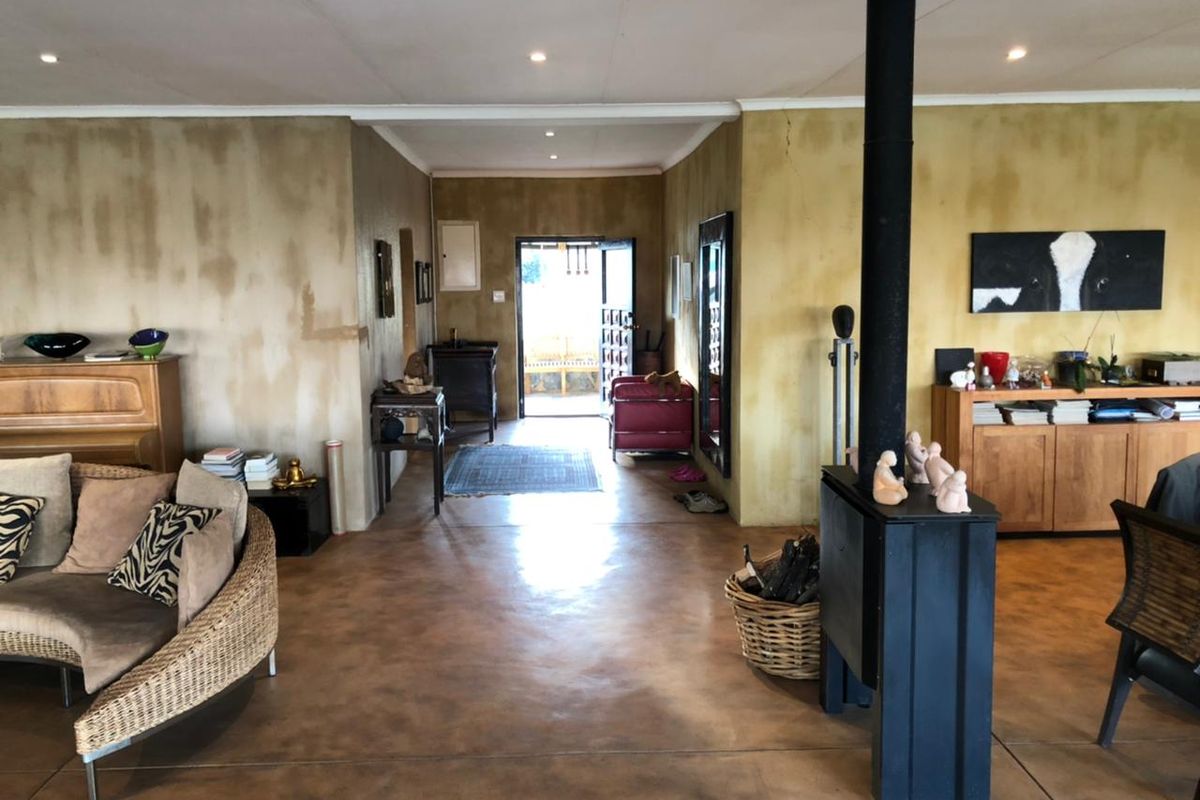 Spacious living area featuring polished concrete floors and a central freestanding fireplace, leading towards an entrance hall.