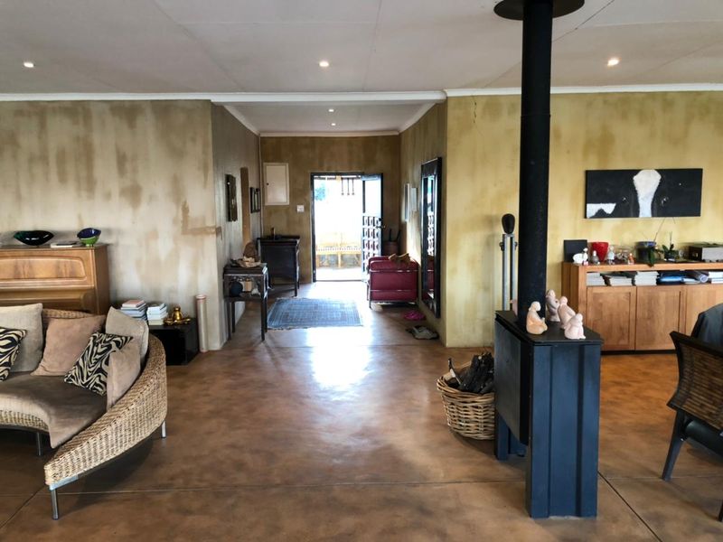 Spacious living area featuring polished concrete floors and a central freestanding fireplace, leading towards an entrance hall.