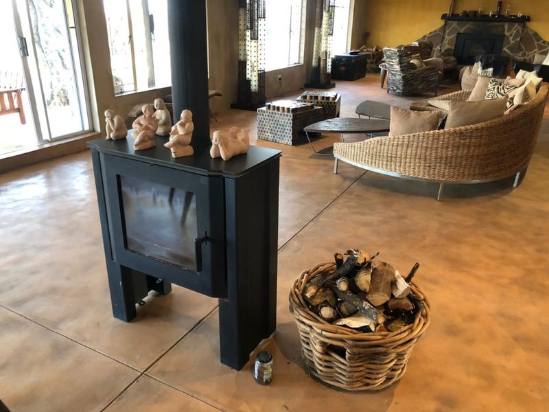 Spacious living area featuring polished concrete floors, a modern freestanding fireplace, and a secondary stone-clad fireplace, with large sliding doors providing natural light.