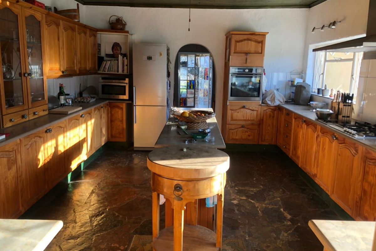 Spacious rustic kitchen featuring extensive wooden cabinetry, stone flooring, timber ceiling, and integrated appliances, offering a warm and traditional aesthetic.