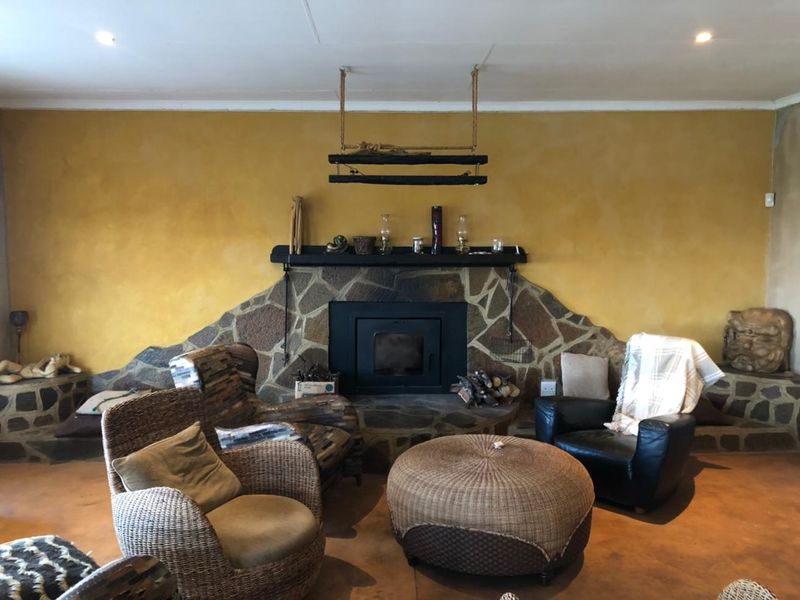 A cozy living room featuring a prominent built-in stone fireplace with a closed combustion insert and warm-toned concrete flooring.