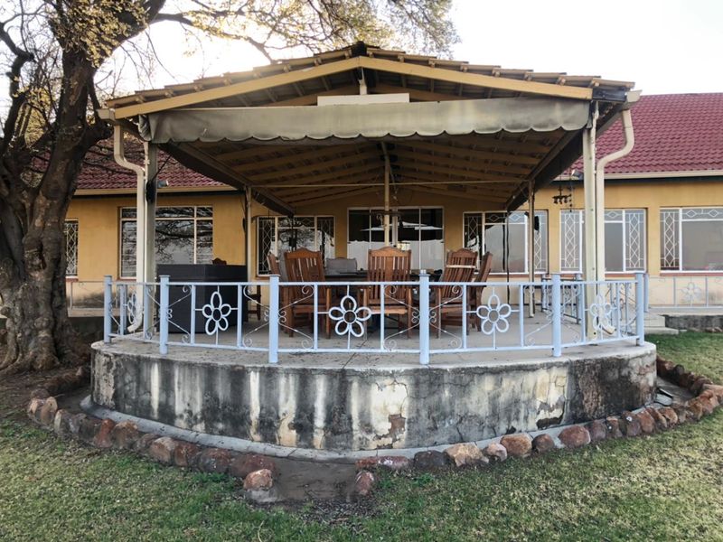 A covered outdoor patio area featuring a wrought iron balustrade and a concrete base, requiring maintenance to the foundation and exterior finishes.