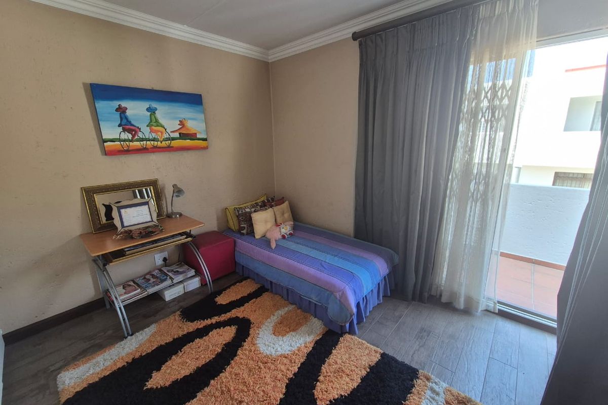 A bedroom featuring wood-look tiled flooring, crown molding, and a sliding glass door providing access to an outdoor balcony area.