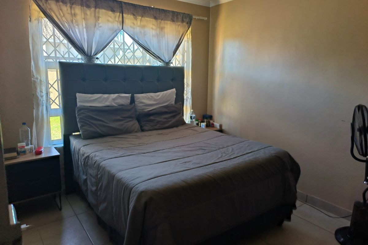 A bedroom featuring tiled flooring and a window with security bars, providing natural light to the space.