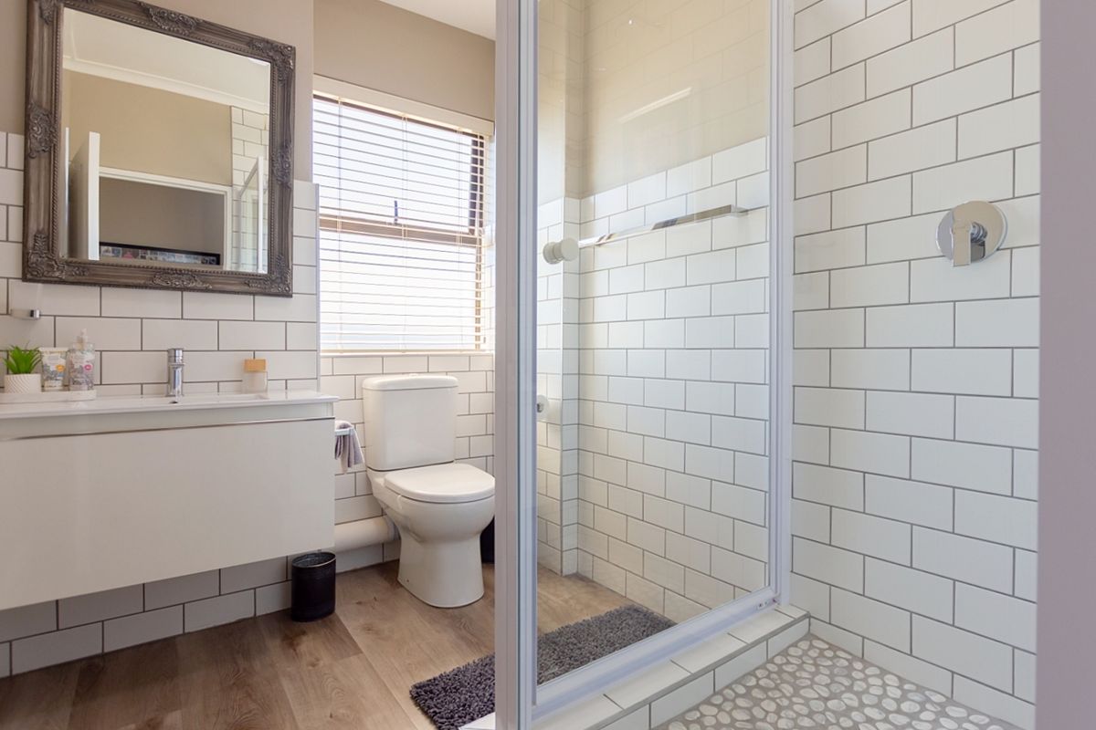 Modern bathroom featuring a wall-mounted vanity, subway-tiled walls, and a glass-enclosed shower with pebble flooring.
