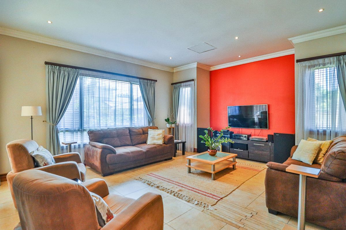 Spacious living room featuring large windows, tiled flooring, recessed ceiling lighting, and a bold accent wall.