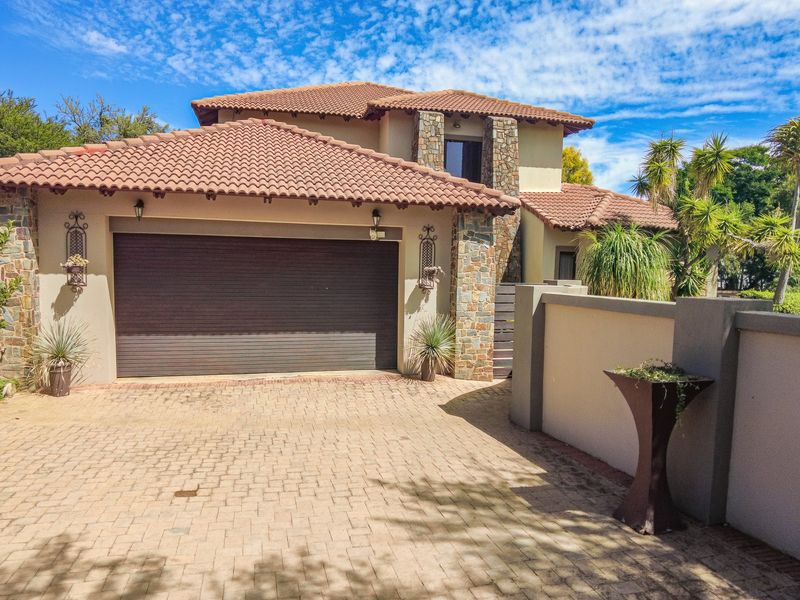 Front exterior view of a double-story house featuring a paved driveway, double garage, and stone-clad architectural accents.