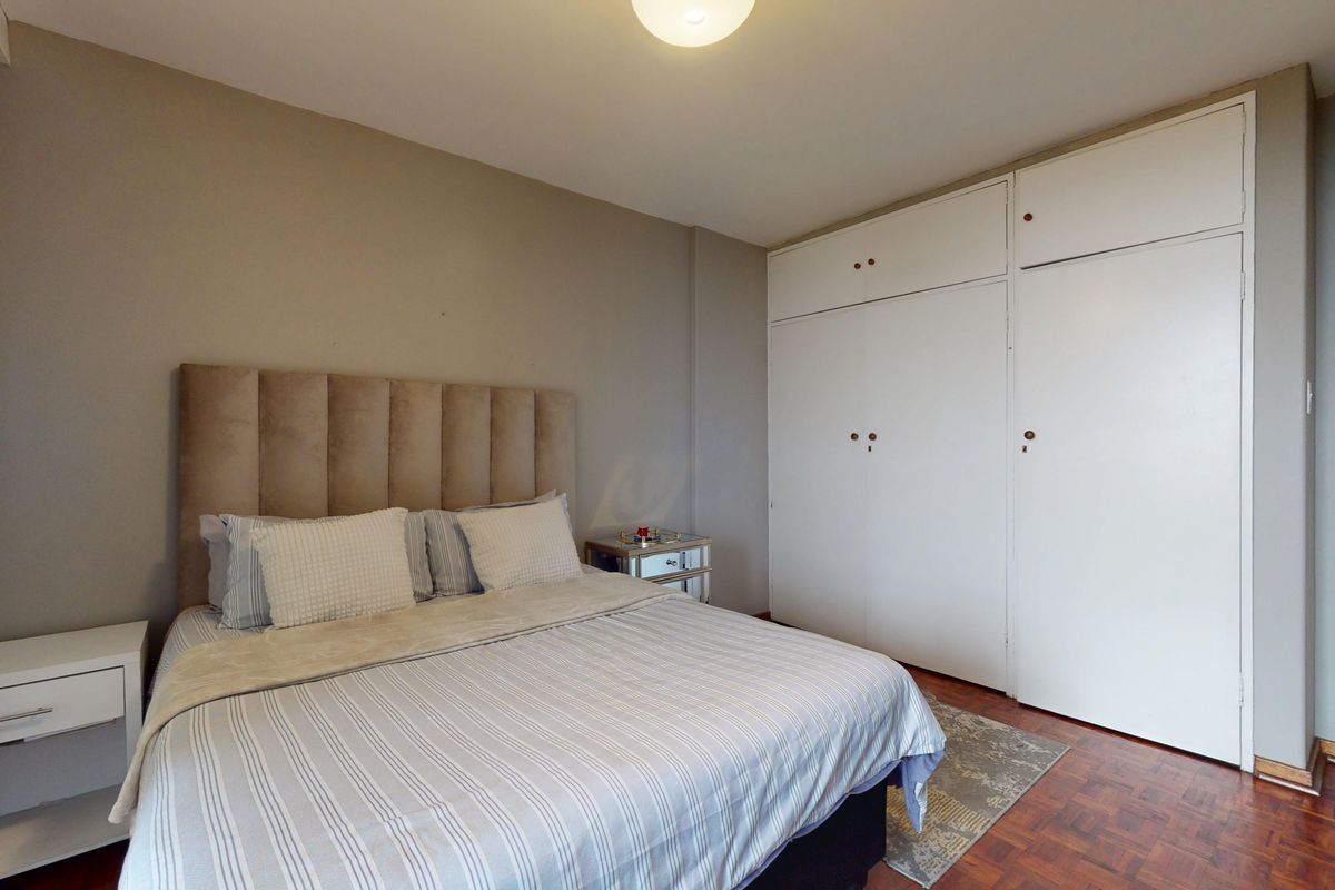 A bedroom featuring parquet flooring and ample built-in cupboard storage space.