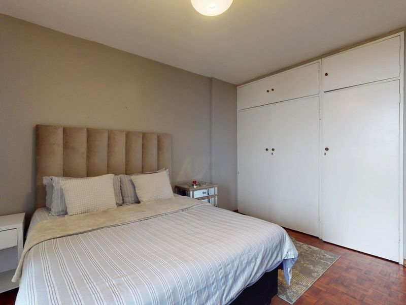 A bedroom featuring parquet flooring and ample built-in cupboard storage space.