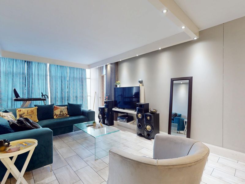 A well-lit living room featuring modern tiled flooring and recessed ceiling lighting, creating a comfortable and functional space for relaxation.