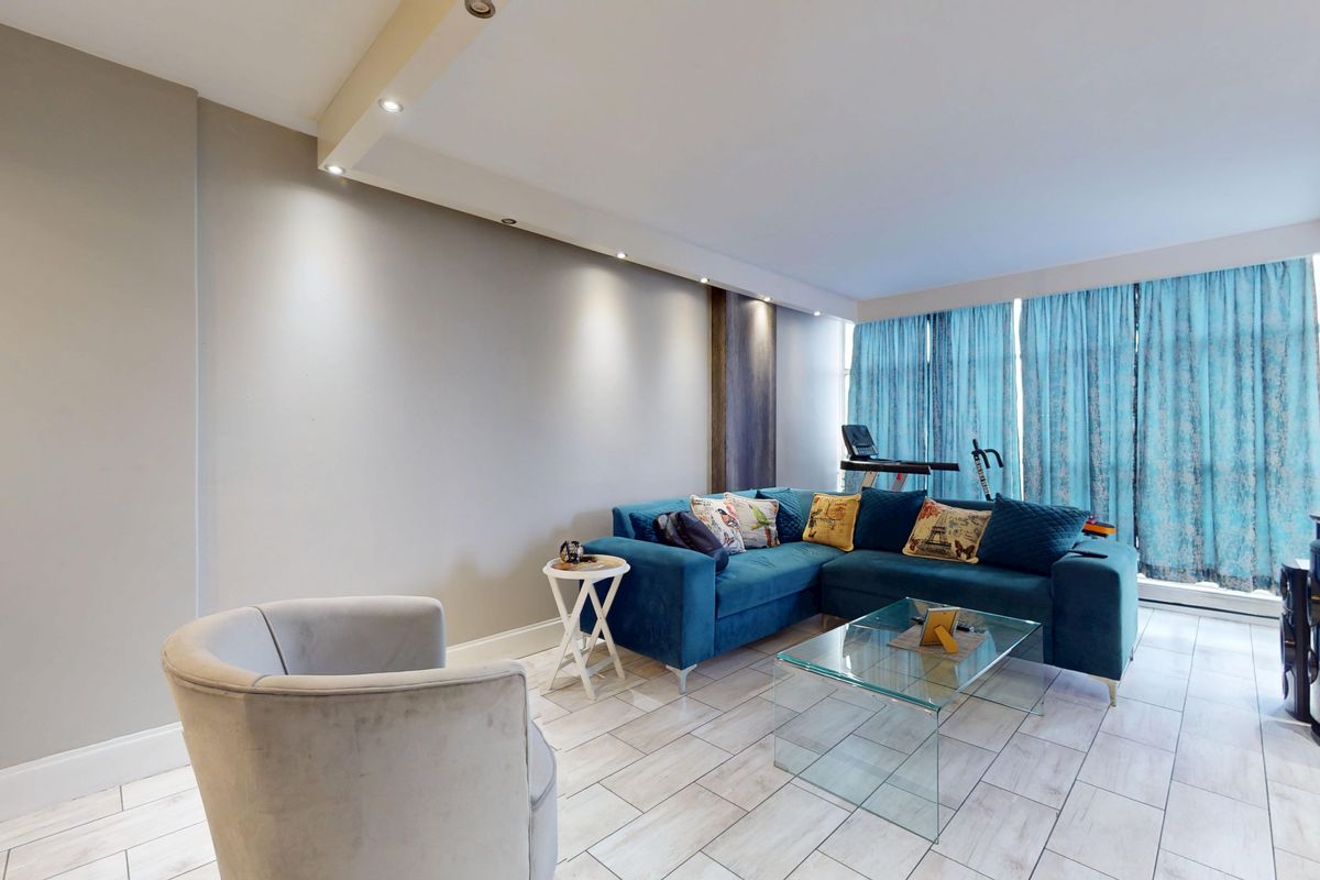 A bright living room featuring tiled flooring, recessed ceiling lighting, and large windows allowing for ample natural light.