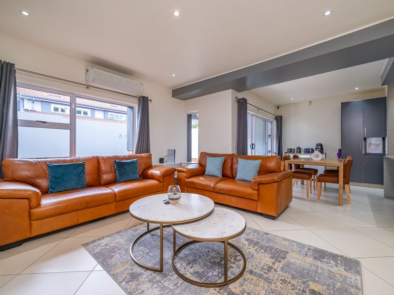 Spacious open-plan living and dining area featuring tiled floors, recessed lighting, and a split-system air conditioner, seamlessly connected to the kitchen.