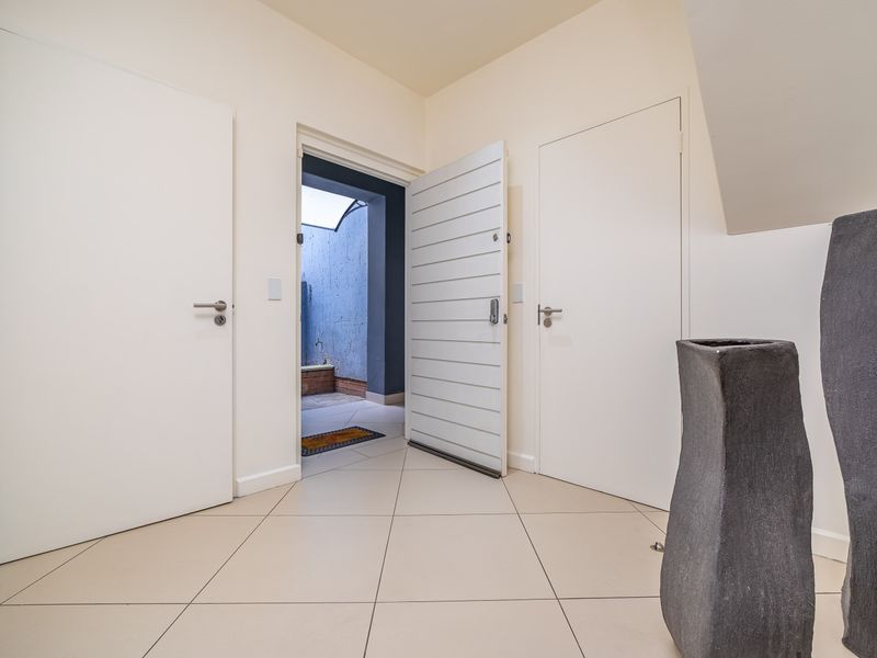 A bright and clean entrance foyer featuring neutral tiled flooring and multiple internal doors leading to various areas of the townhouse.