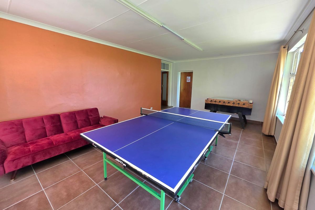 A multi-purpose living area featuring tiled flooring and neutral wall finishes, currently utilized as a recreational space.