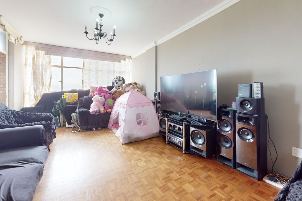 A living room featuring classic parquet flooring, decorative ceiling coving, and a large window providing natural light.