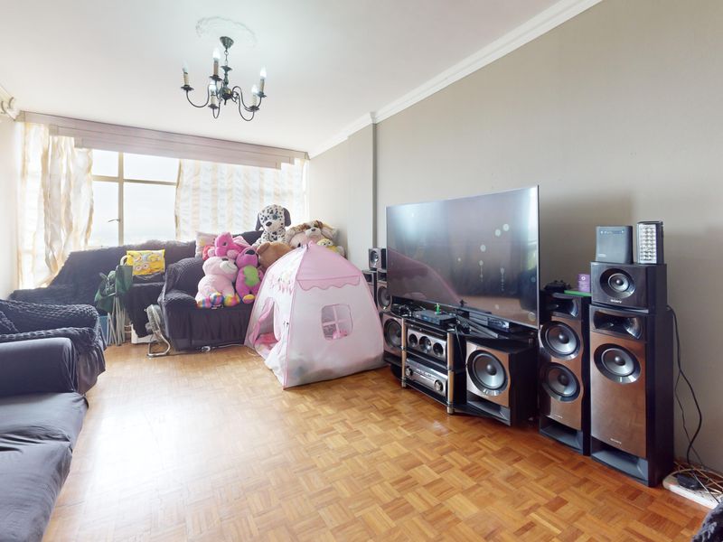 A living room featuring classic parquet flooring, decorative ceiling coving, and a large window providing natural light.